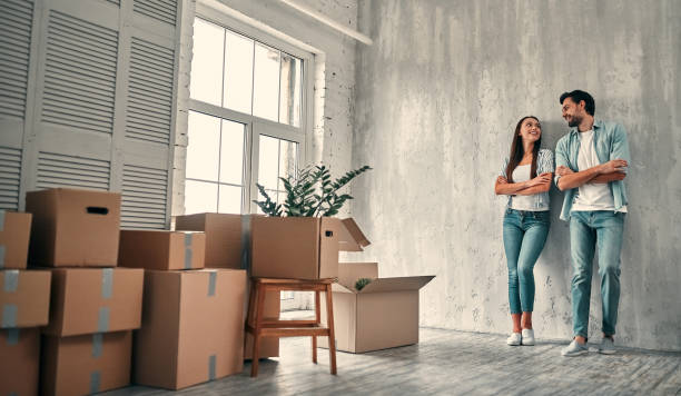 Couple on moving day. Attractive young woman and handsome bearded man with cardboard moving boxes are happy to move into new home with movers and packers in Dubai.